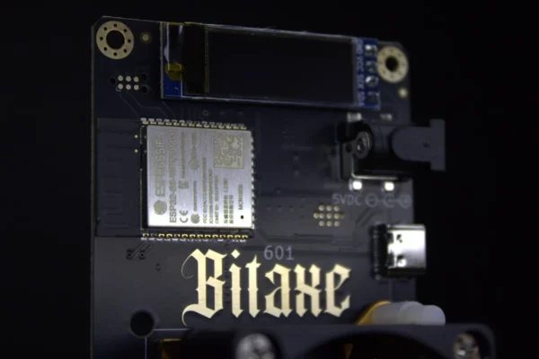 Bitaxe Gamma PCB close-up showing ESP32-S3 Wi-Fi module, OLED stats screen and USB-C port on open-source Bitcoin miner