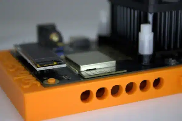 Side profile of Bitaxe Gamma solo miner highlighting Wi-Fi module OLED screen and Dark Horse heatsink on orange stand