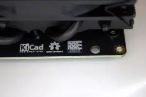 Close-up of NerdQaxe++ PCB corner showing “KiCad,” open-hardware gear, and “Assembled in the USA” badges.