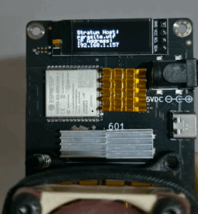 Bitaxe miner device displaying "Stratum Host: parasite.wtf" and local IP address "192.168.1.157" on its OLED screen.
