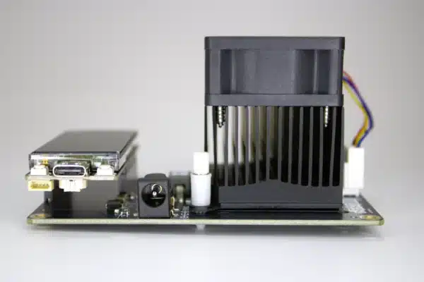 “NerdAxe Gamma Bitcoin miner side view showing large black heatsink-fan combo, USB-C OLED control board and 5 V DC jack.”
