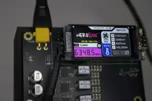 Close-up of NerdQaxe++ Rev 6 OLED screen showing 6.3 TH/s, XT30 power jack, and upgraded copper-trace PCB
