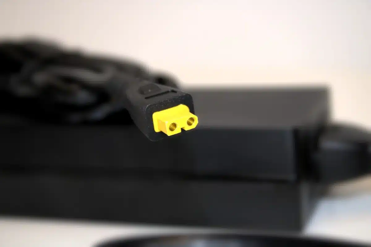 Yellow XT30 power plug on NerdQaxe Rev 6 power-brick cable, close-up against blurred black adapter