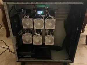 Open PC tower with six NerdQaxe++ Revision 6 miners in a three by two grid, each with white fans, and a small screen at the top reading Block Found.