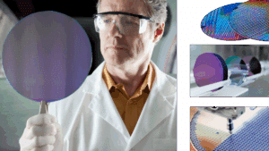 Lab technician wearing safety glasses holds and inspects a round silicon wafer used to manufacture computer chips.