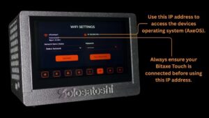 Annotated photo of a Bitaxe Turbo Touch Bitcoin miner showing the WiFi Settings screen in a connected state, with callouts highlighting the IP address used to access the device's operating system (AxeOS) and a reminder to ensure the device is connected before using the IP address.