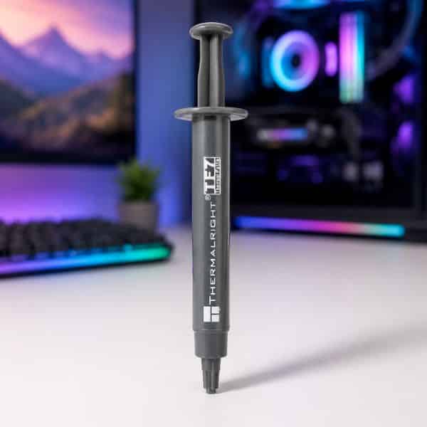 Thermalright TF7 thermal paste 2g tube standing upright on desk with RGB PC build and monitor in background